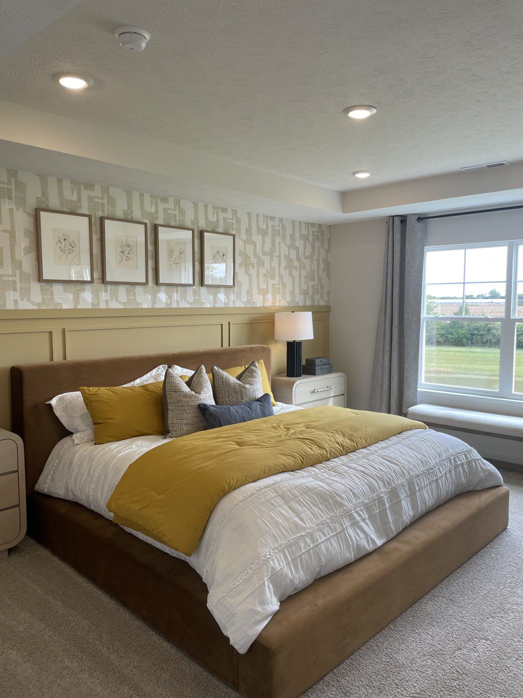 A staged bedroom with neutral bedding and framed art